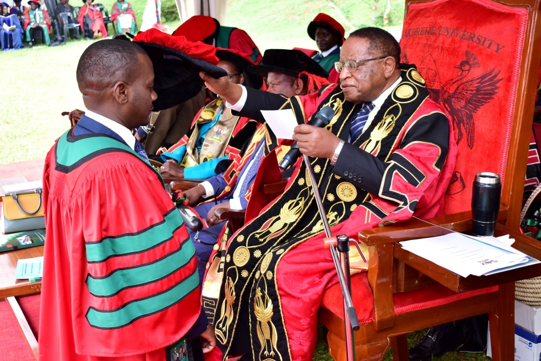 The Chancellor, Prof. Ezra Suruma (R) confers the Doctor of Philosophy upon Dr. John Kalule from CEES (L) during the Second Session of the 72nd Graduation Ceremony of Makerere University held on 24th May 2022 in the Freedom Square.